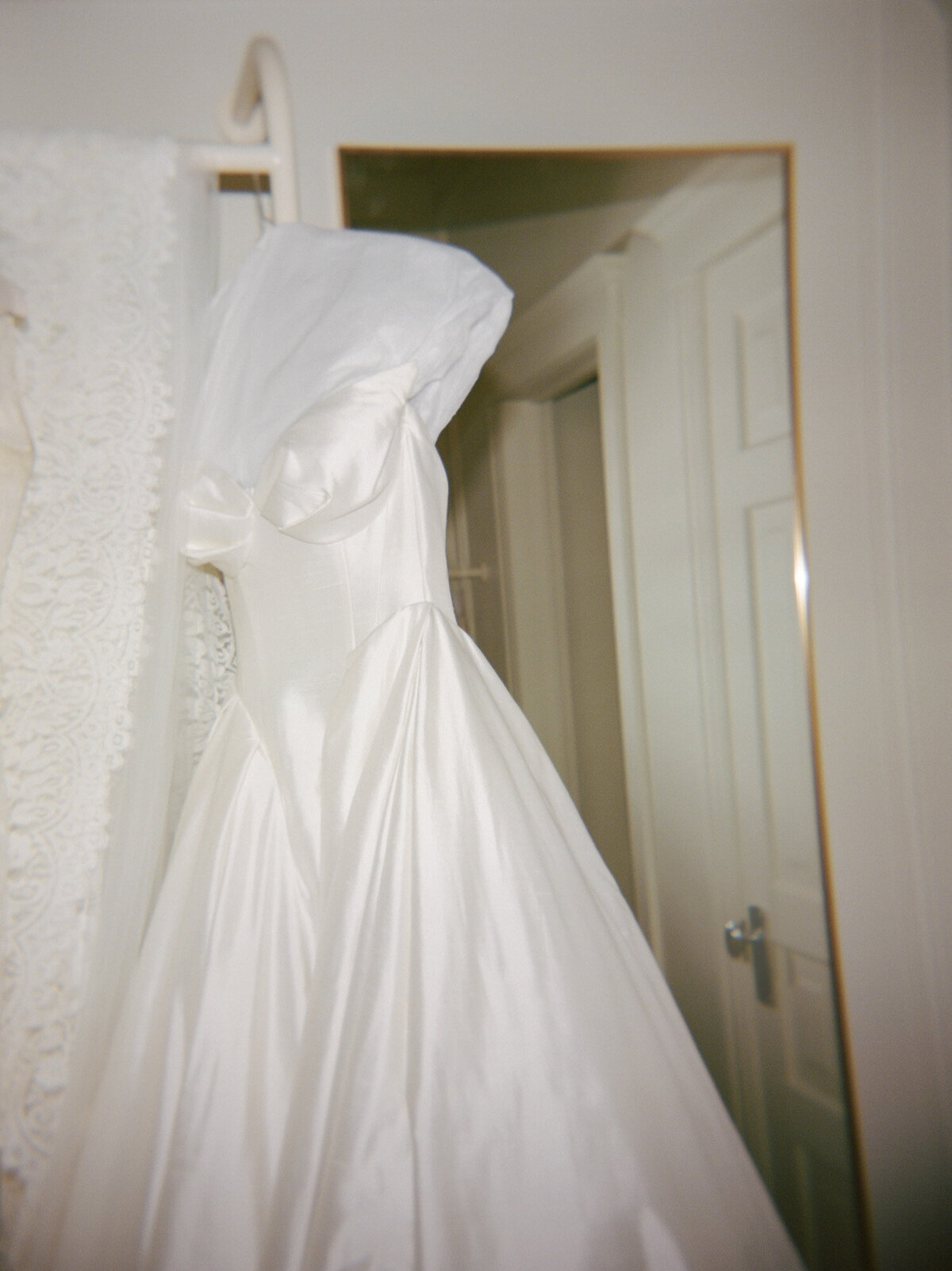 still with its crisp tissue insert, a raw silk Leah Dagloria wedding dress hangs in the penthouse at 1 Room Hotel, a unique wedding getting ready venue in Detroit