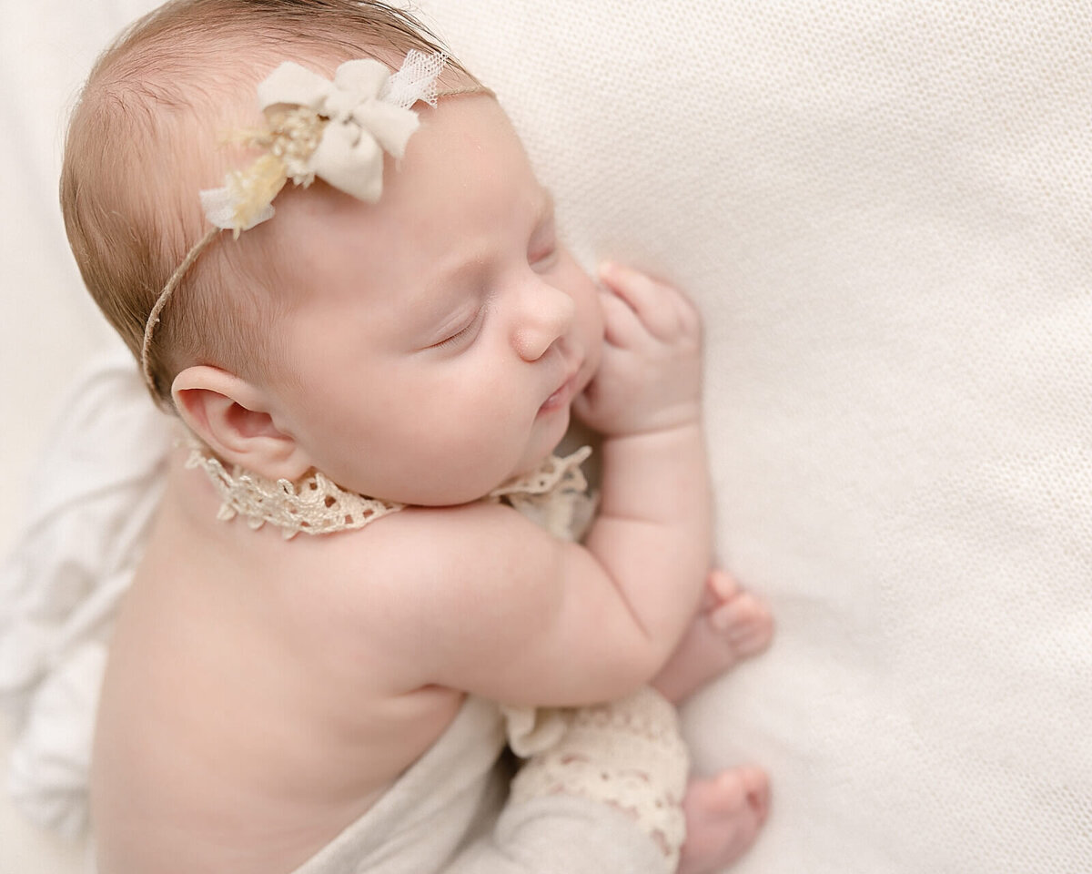 baby girl in cream romper with headband on taken by portland baby photographer Ann Marshall.