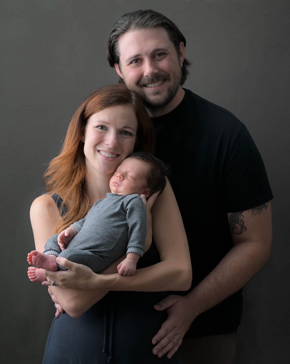 Beth Benecki captures a new mom and dad with their newborn son in a family photo where mom is holding baby and dad is snuggled in close to them.
