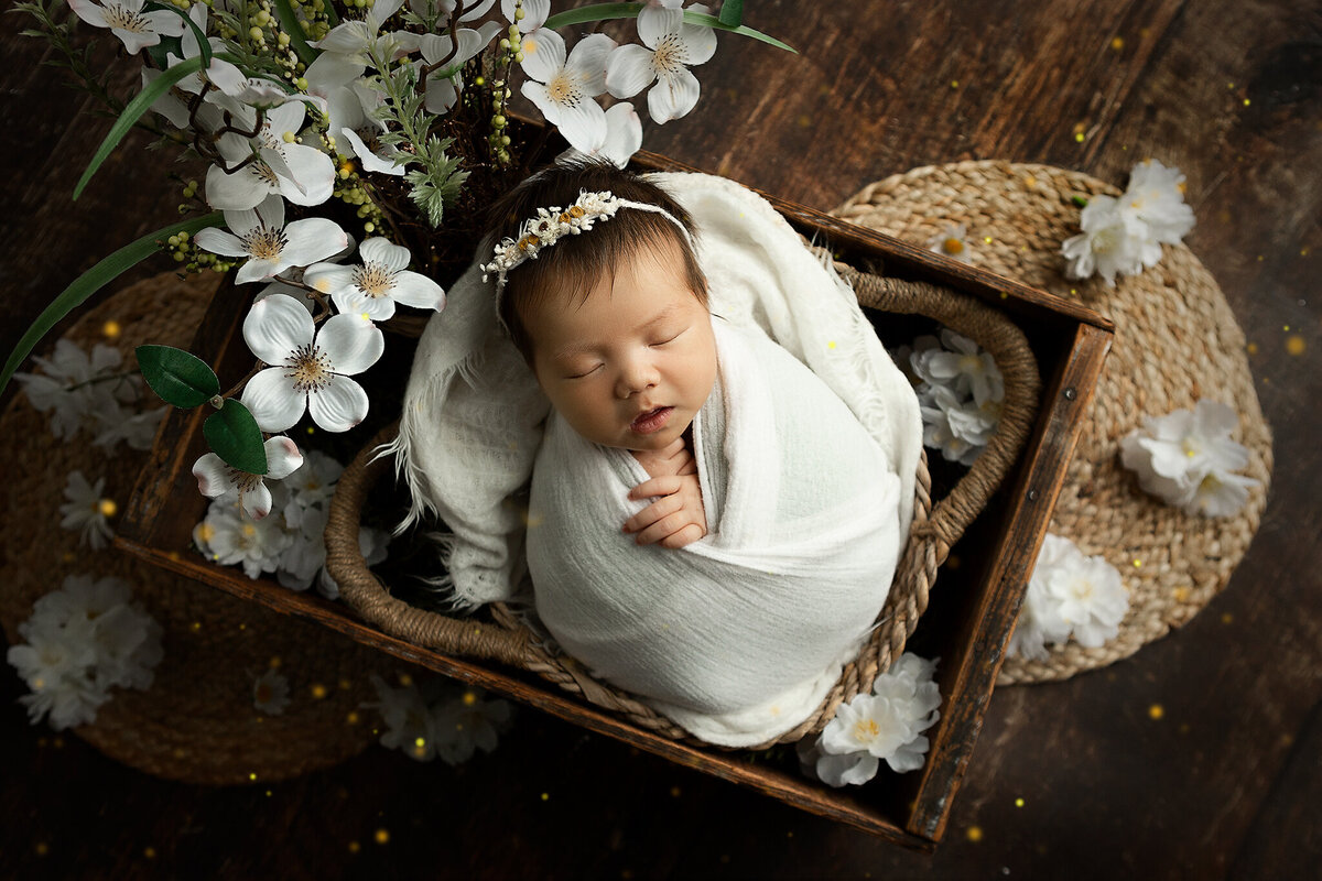 hilliard-ohio-newborn-baby-girl-swaddled-in-white-in-basket-with-flowers