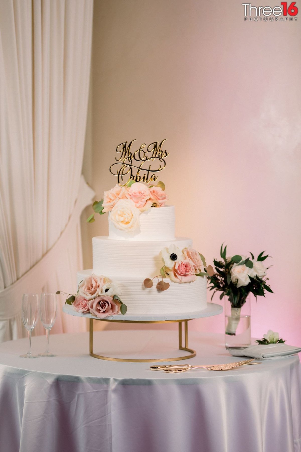 White three-tiered wedding cake awaits the wedding reception
