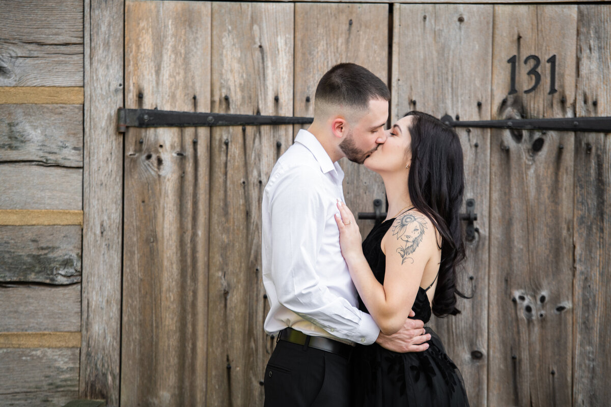 engaged_couple_steal_kiss_farm_doors