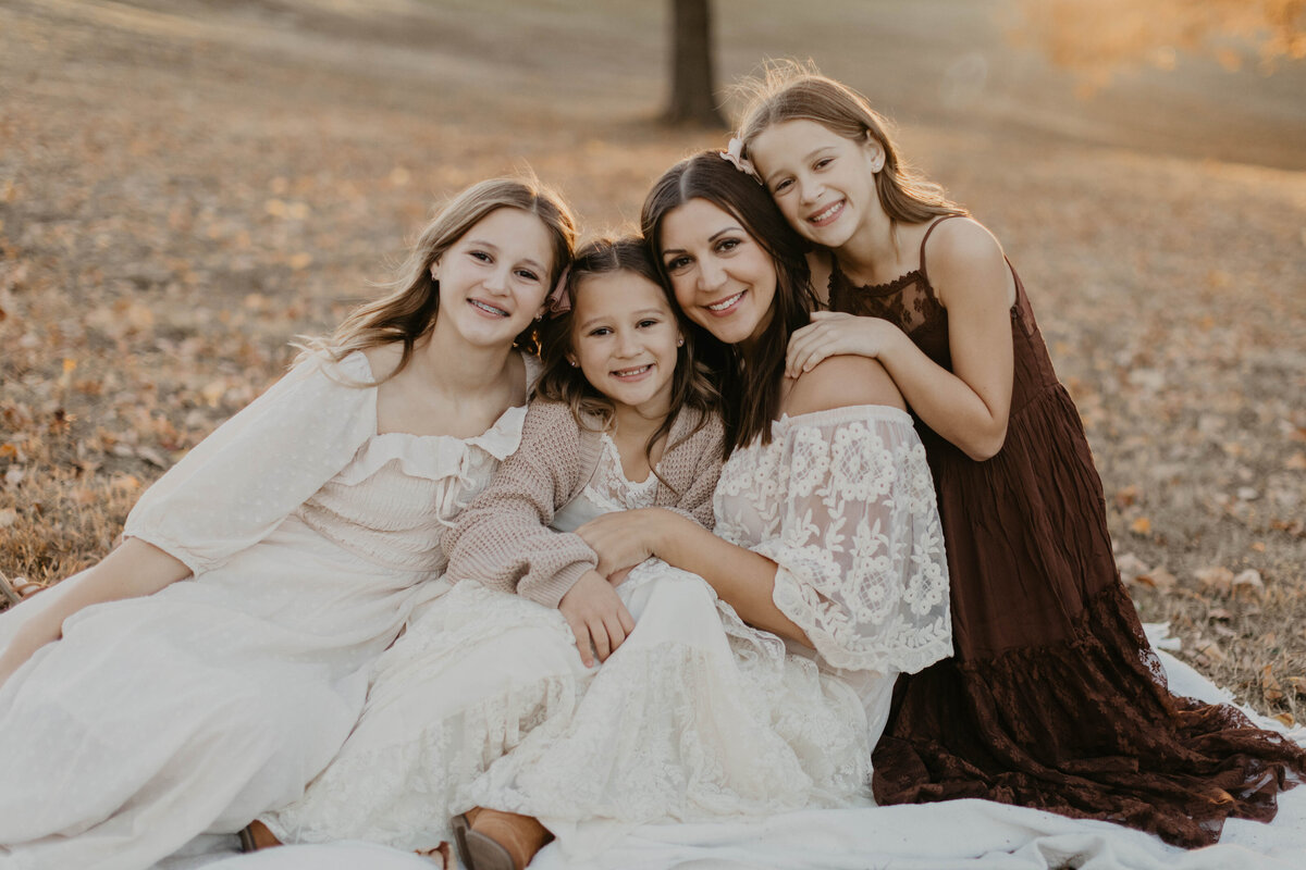mom and 3 girls sitting together in warm embrace. 