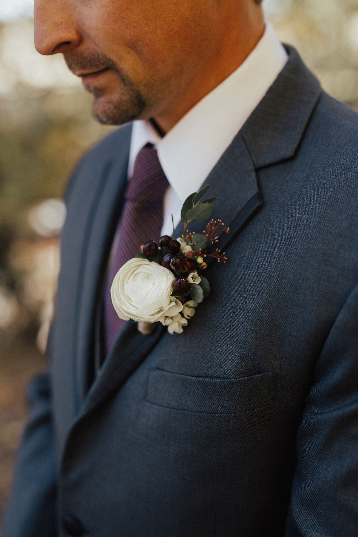 White ranunculus with mixed dark accents boutonniere
