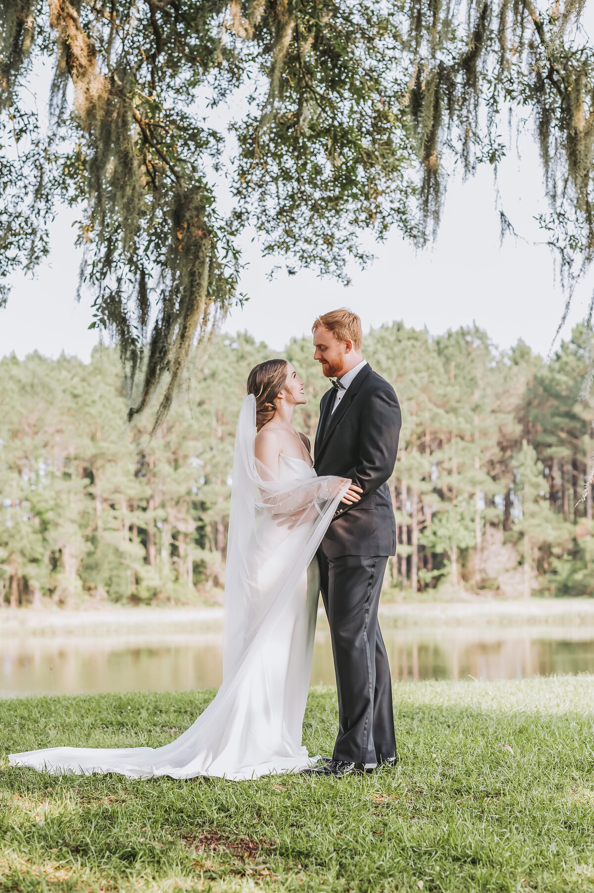Bride and groom gazing into each others eyes under spanish moss