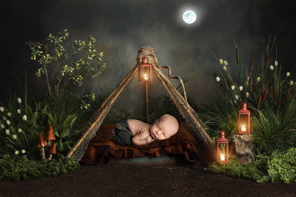 baby boy in gray pants sleeping in a tiny tent in a whimsical night surround