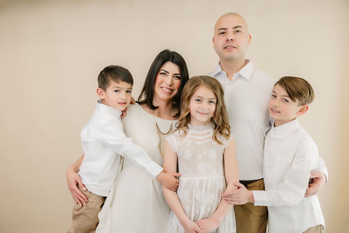 Three children gather around mom and dad in studio smiling