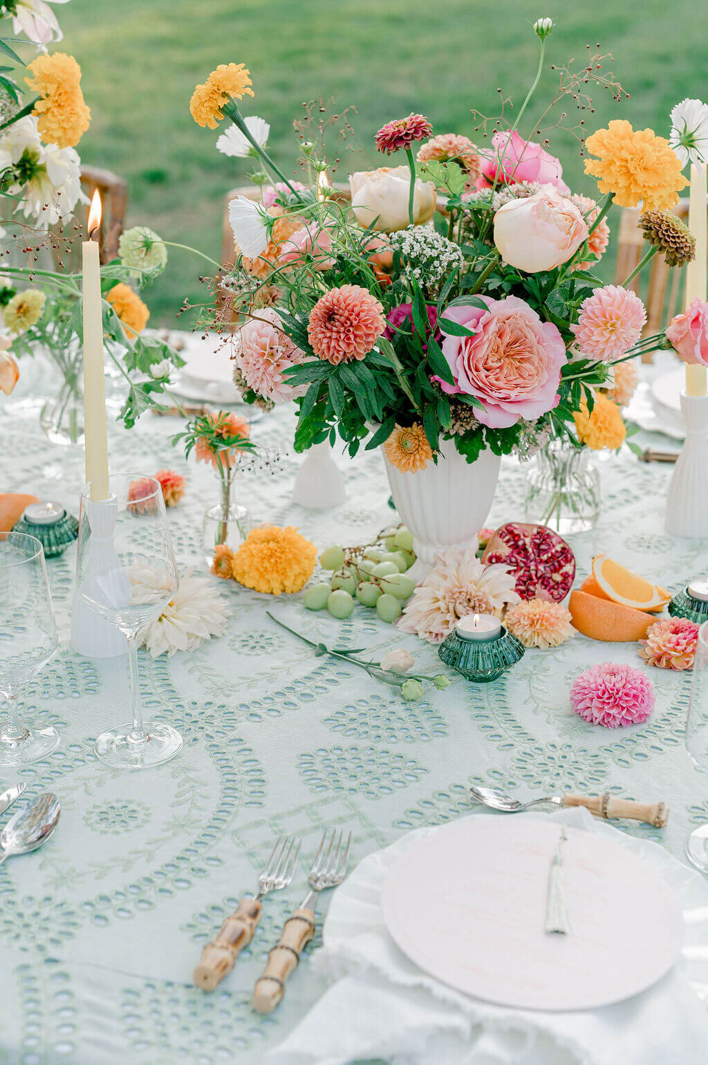 Colorful garden-inspired wedding tablescape with bold florals, citrus fruits, and candlelight.