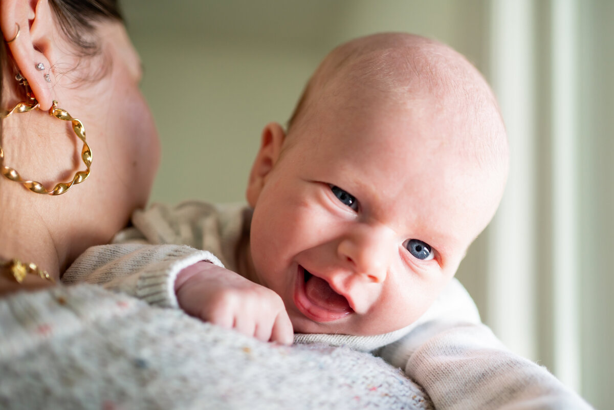 Baby smiling peeking over his mom's shoulder in Sudbury