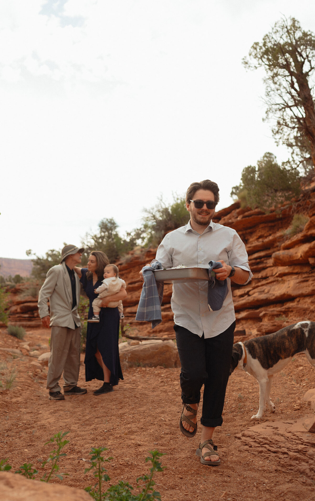 family and dogs gather round and carry food at an elopement in Moab, Utah