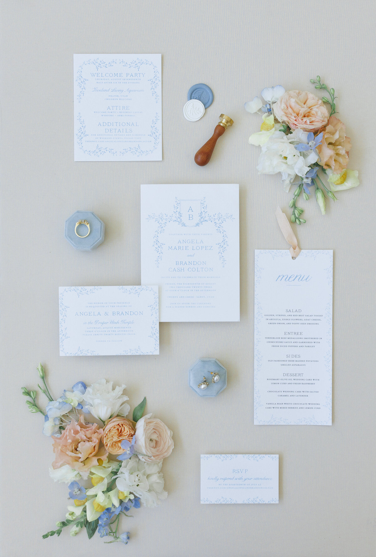 Custom white wedding invitation suite with a baby blue monogram, hand-drawn vines, and soft blue lettering designed by Rose Blossom Weddings.