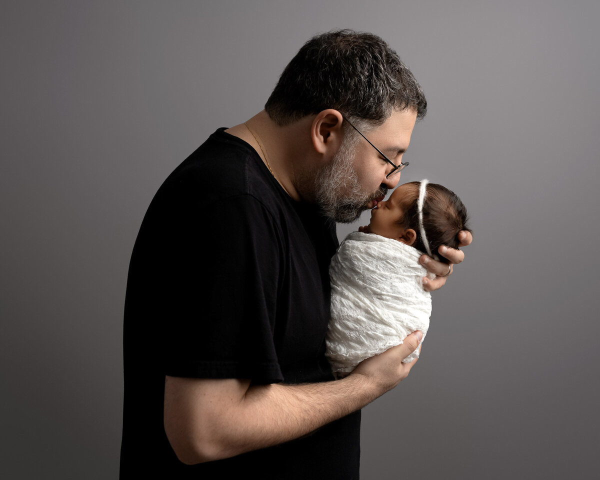 Father holding newborn tender moment Cedar Park family lifestyle photographer