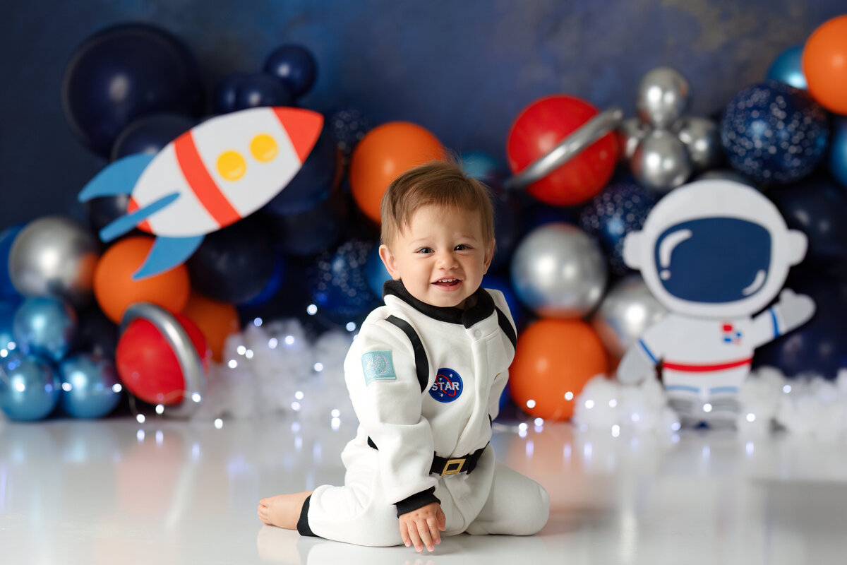 One year old Tampa baby enjoying a personalized luxury cake smash session with playful space themed decorations
