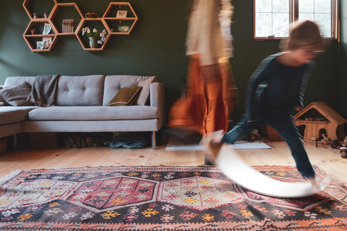 Family life unfolding in a living room full of movement and light, captured by a documentary photographer in Dutchess County.