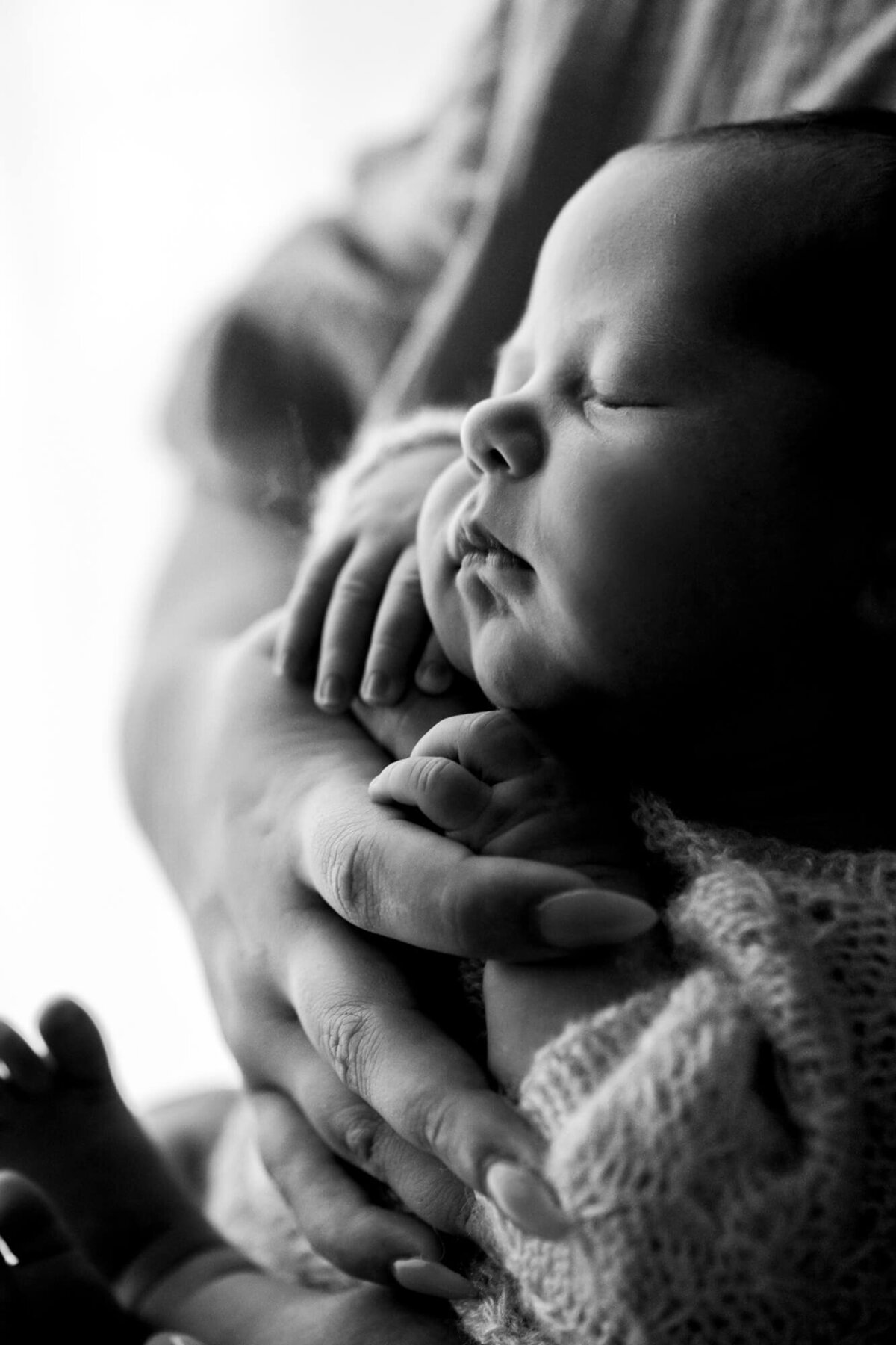 Black and white profile image of a newborn baby boy held in his mother's arms.