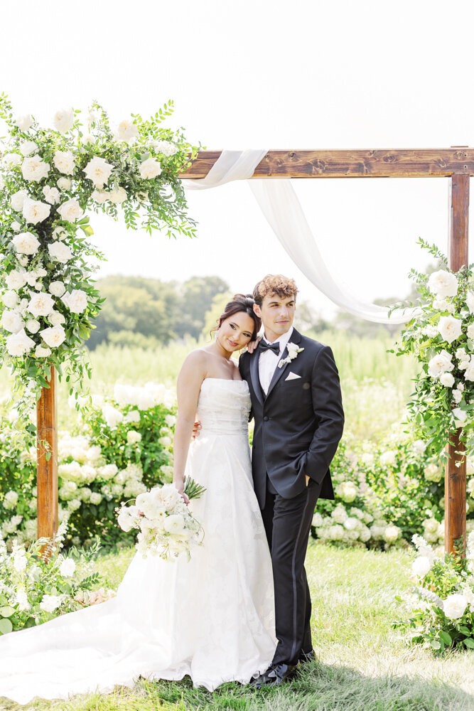 bride and groom posing under an outdoor altar