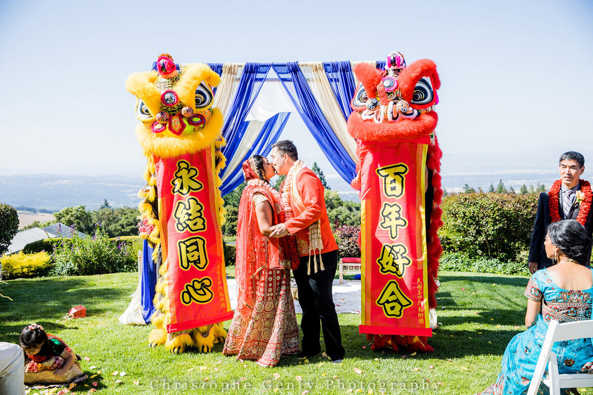 Bride and groom kissing with Chinese dragon dance at their side