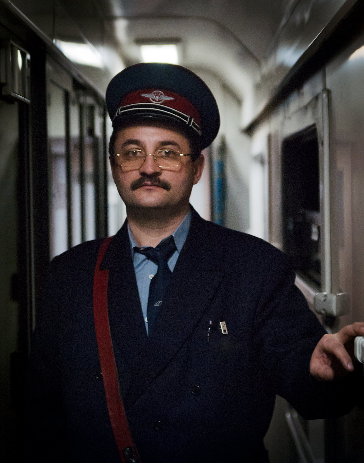 Fotoporträtt av en tågkonduktör i Rumänien under en resa från Karpaterna till Bukarest.