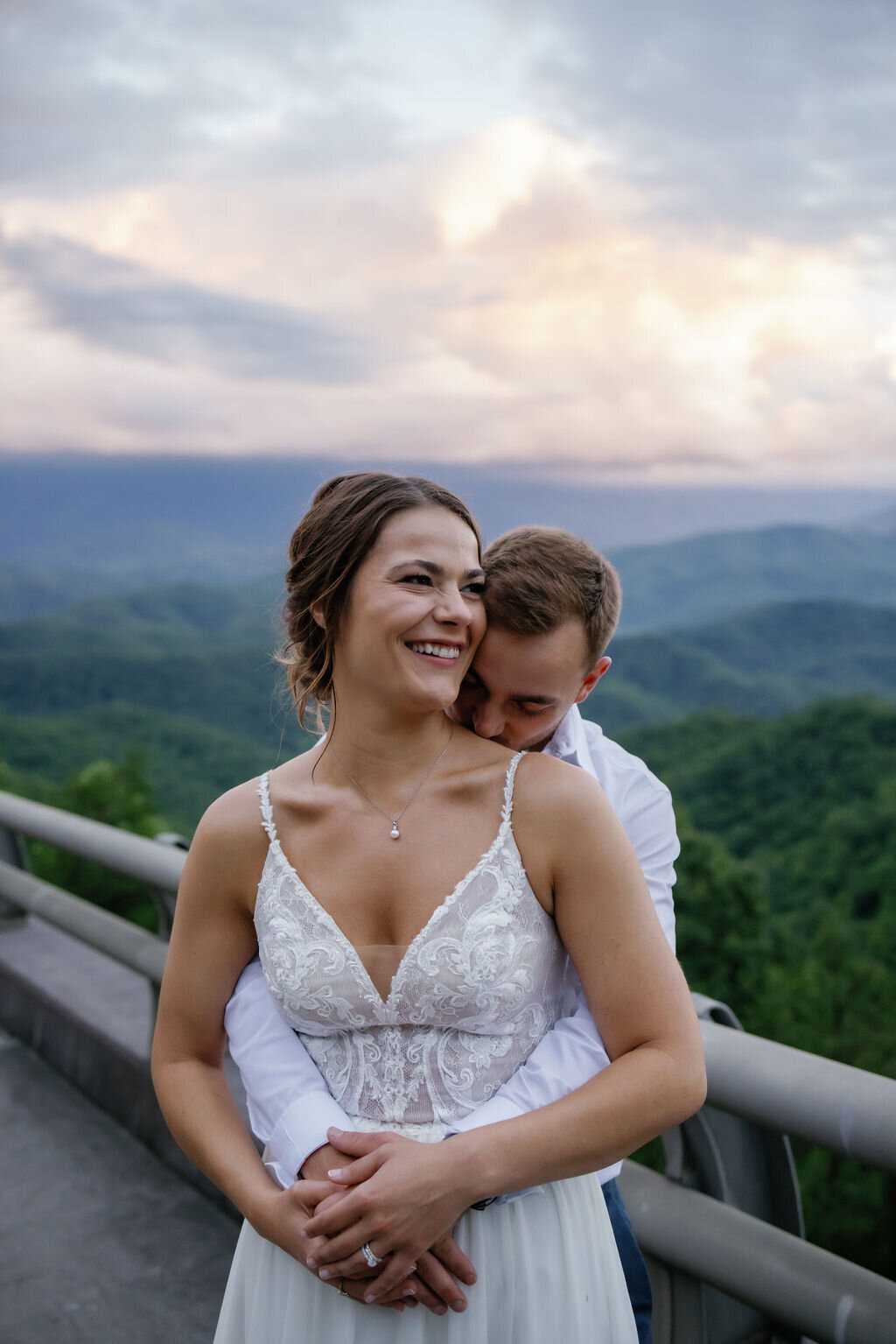 groom holding his bride around the waist and kissing her shoulder for Smoky Mountain elopement photos