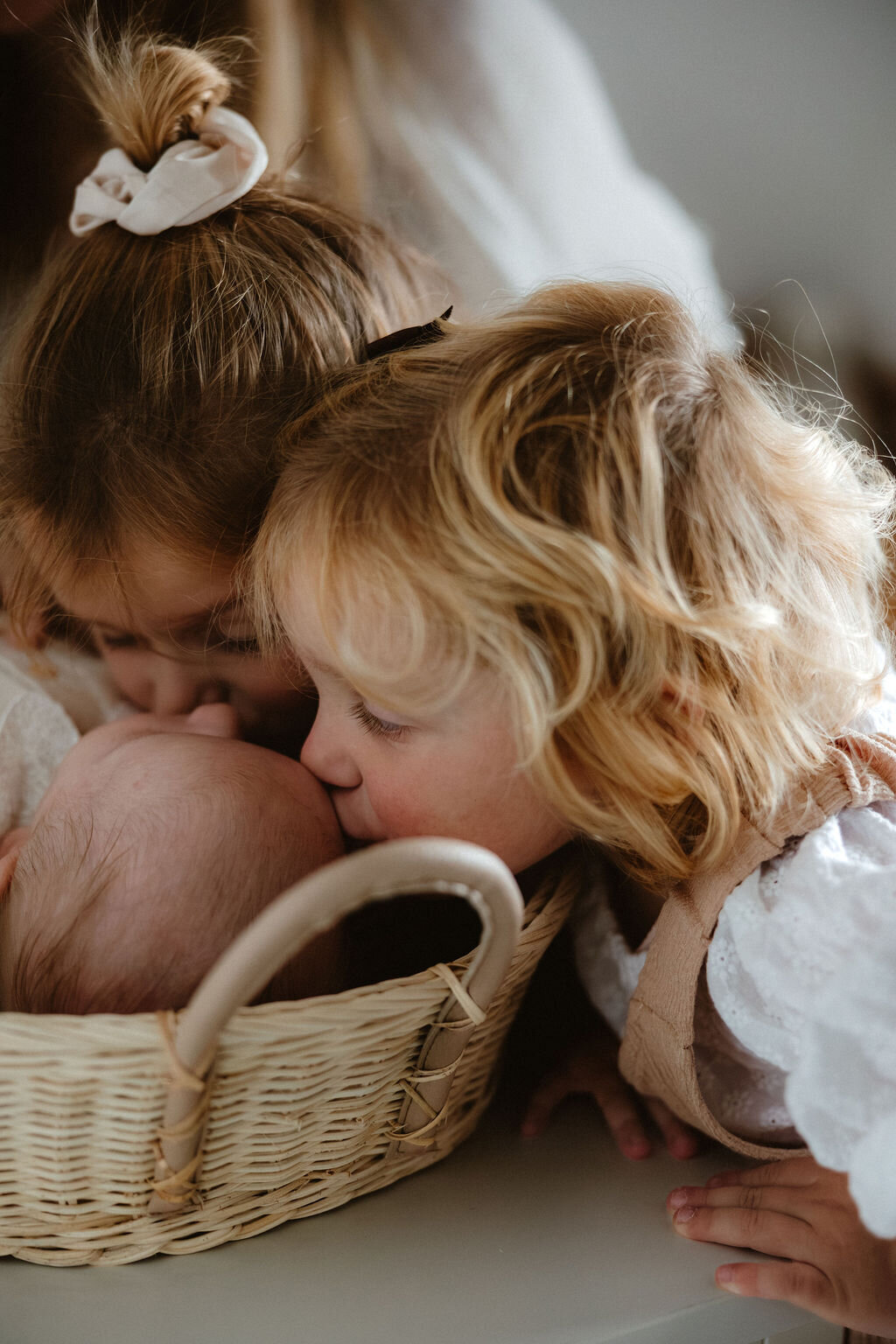 Zusjes geven broertje een zoen tijdens newborn fotoshoot