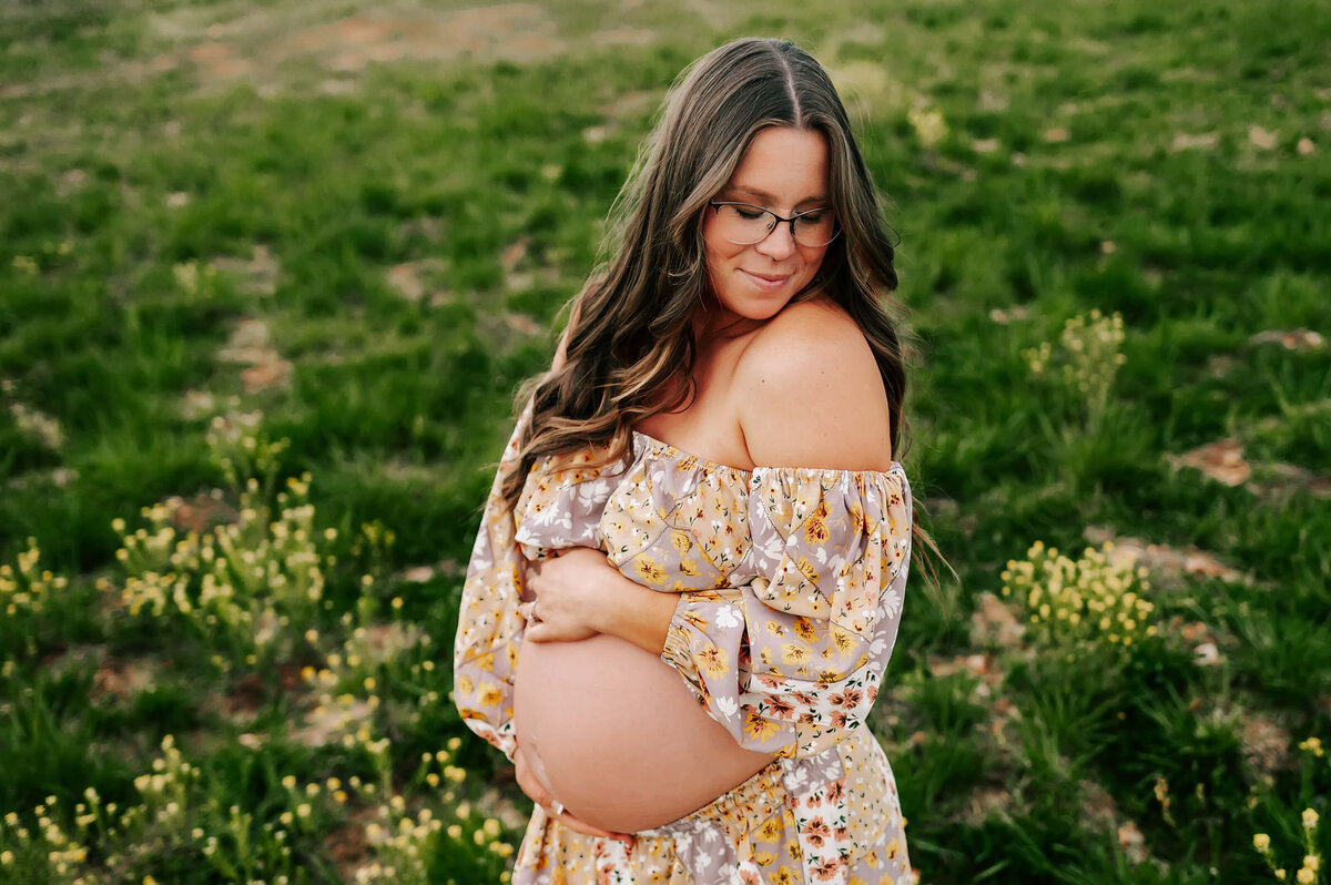 maternity photo in Joplin MO of pregnant mom in floral dress hugging baby bump