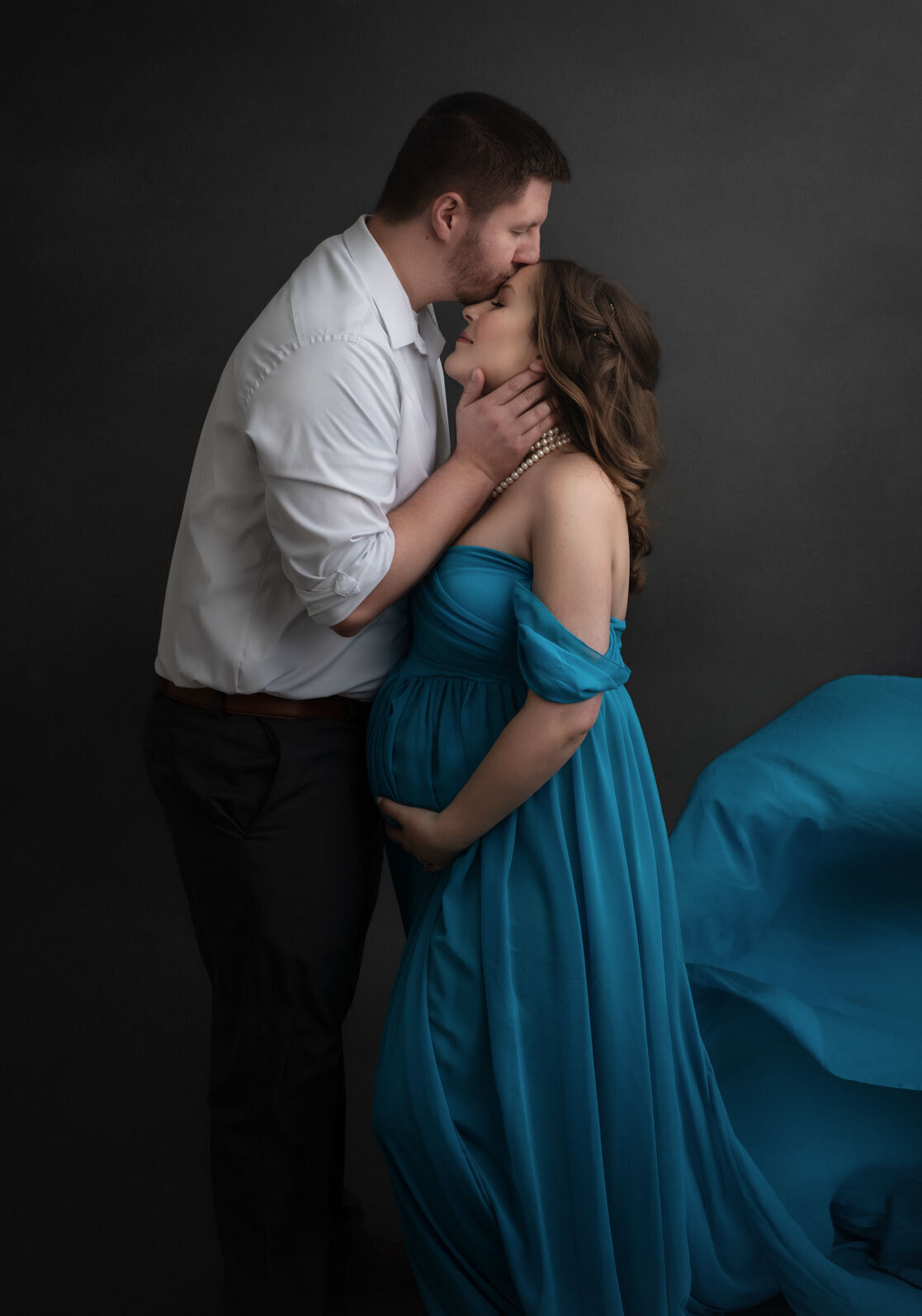 husband kissing wife's forehead at their st. louis maternity photoshoot