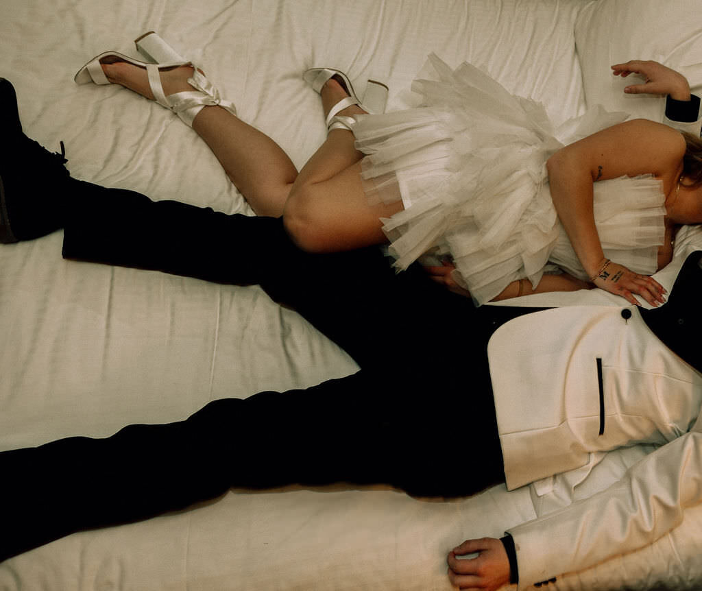 A newlywed couple laying on a bed together.