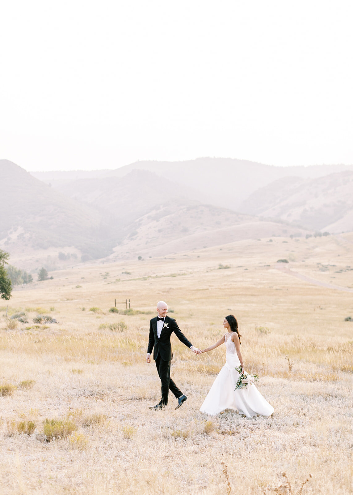 Bride and groom walking through a field at an outdoor Colorado wedding venue