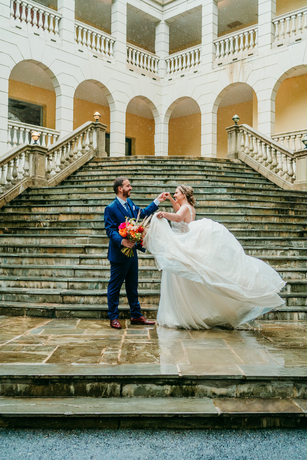 Groom twirling bride on grand staircase at European-inspired venue
