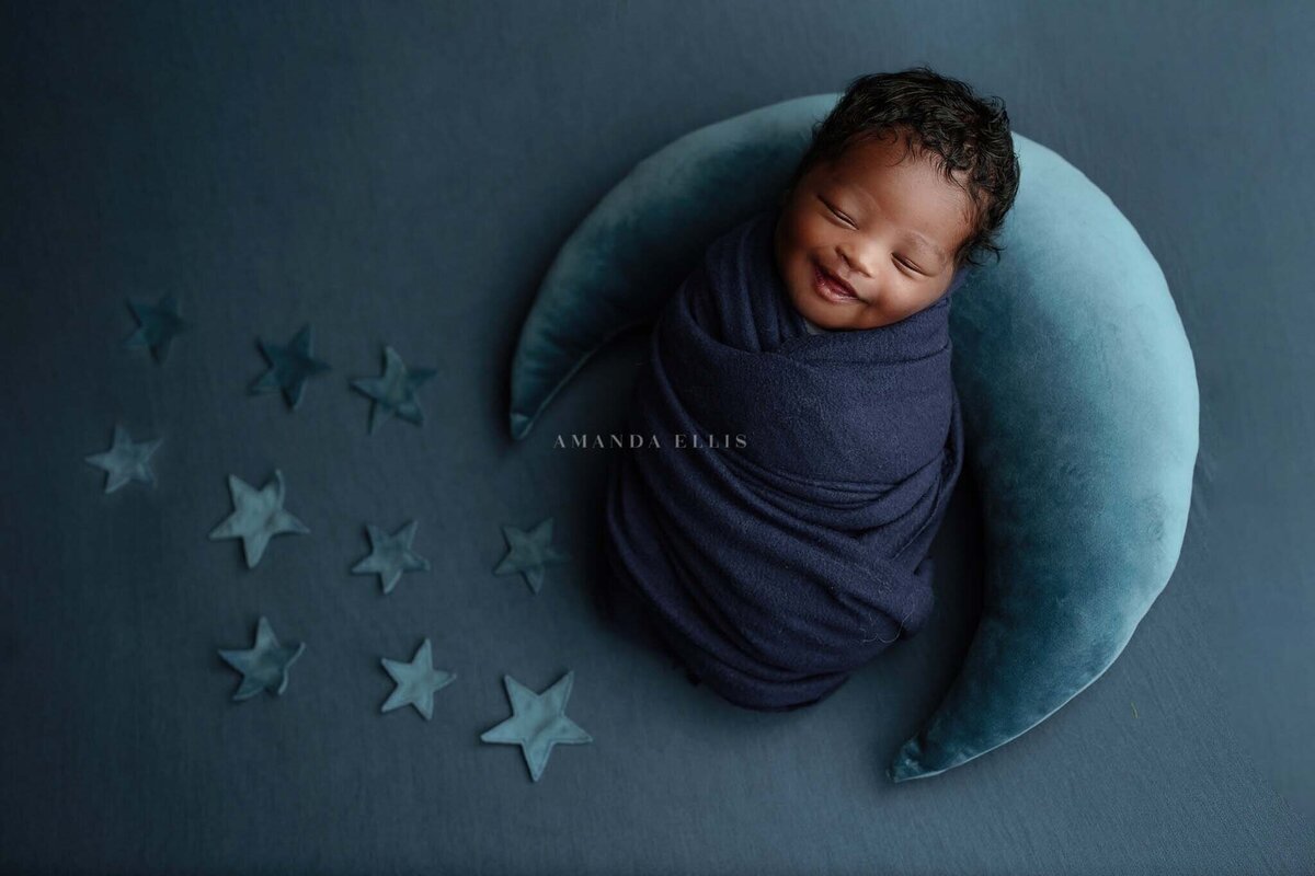 Artistic portrait of baby in moon cushion surrounded by stars