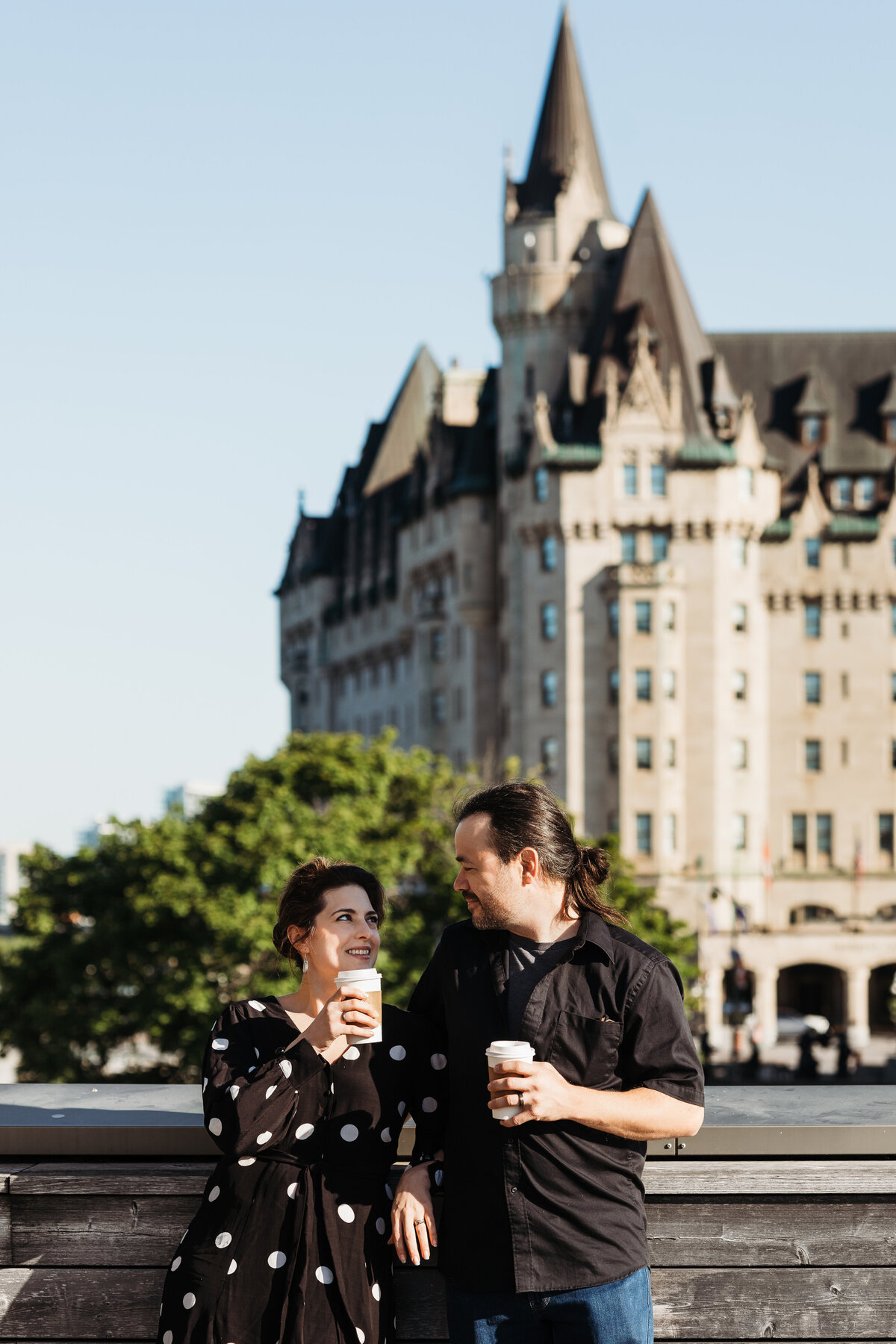 Couple enjoying their morning coffee  with the Chateau Laurier Building behind them