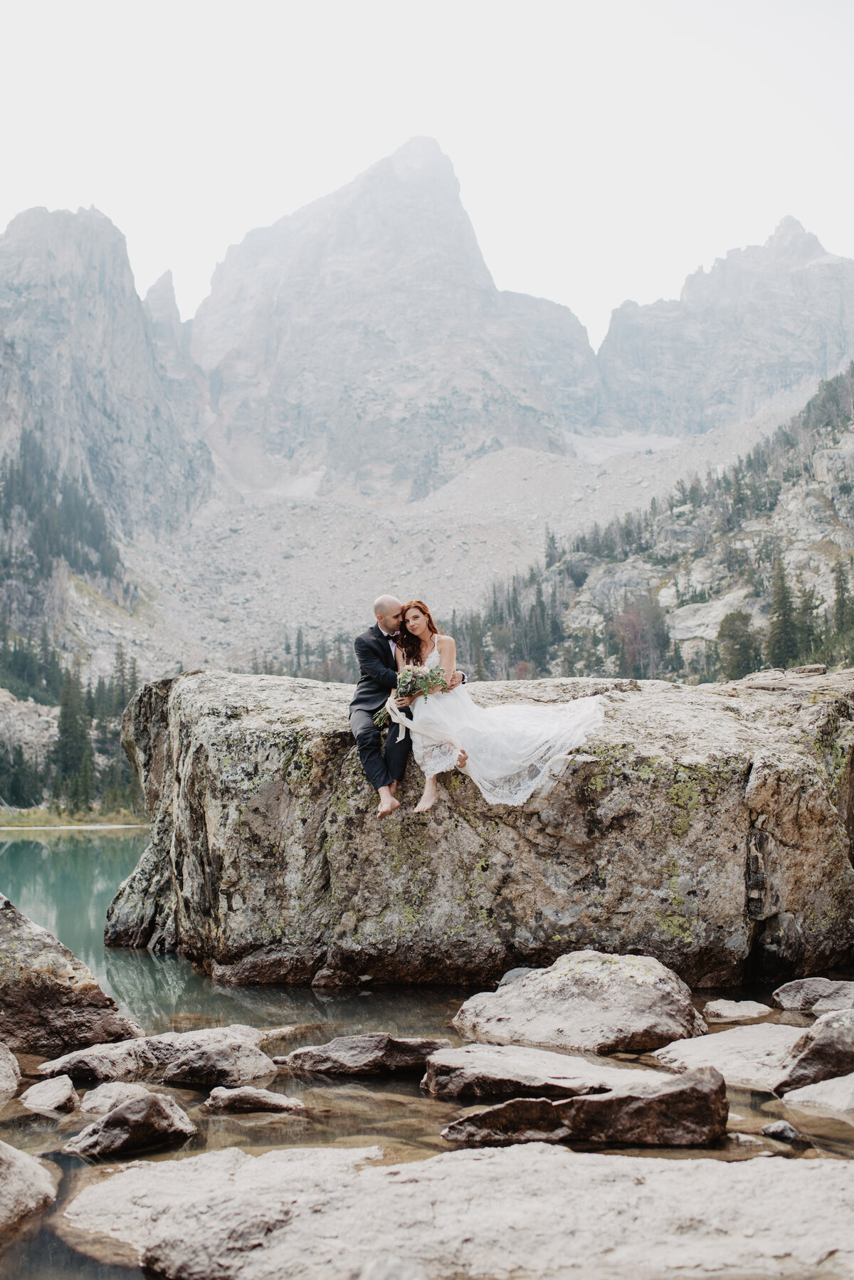 Jackson Hole photographers capture groom hugging bride on boulder in Grand Teton National Park