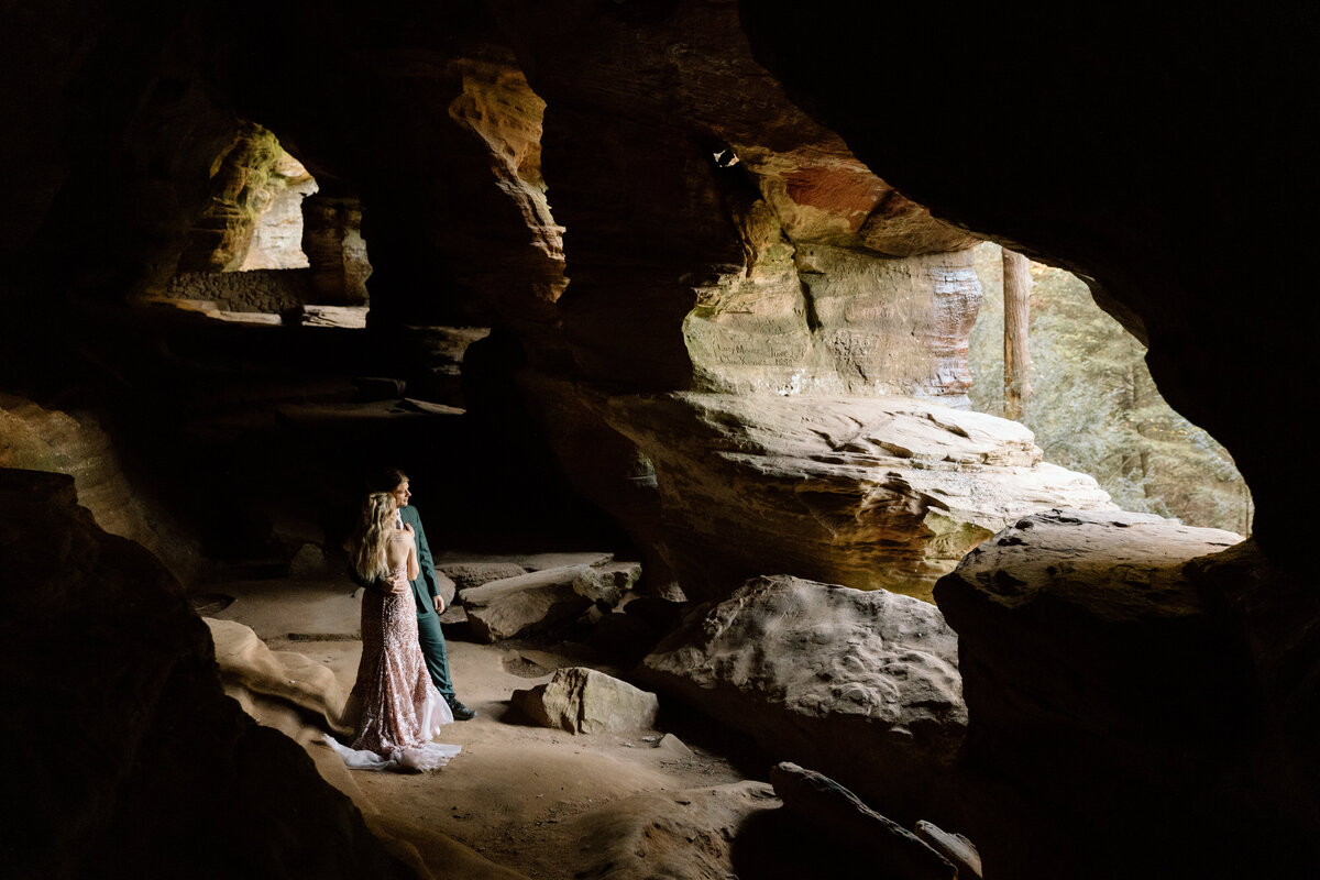 Couple embracing while standing in Rock House's cave.