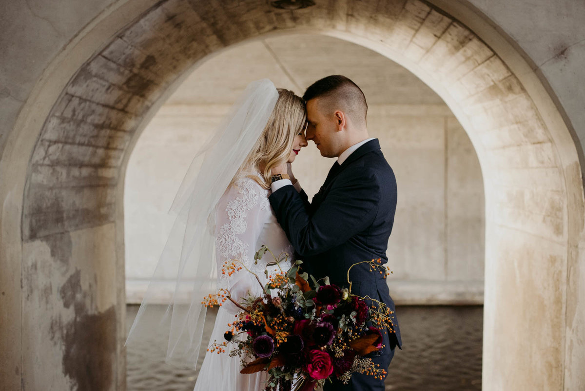 bride and groom at locks by the rideau canal with wild fall bouquet