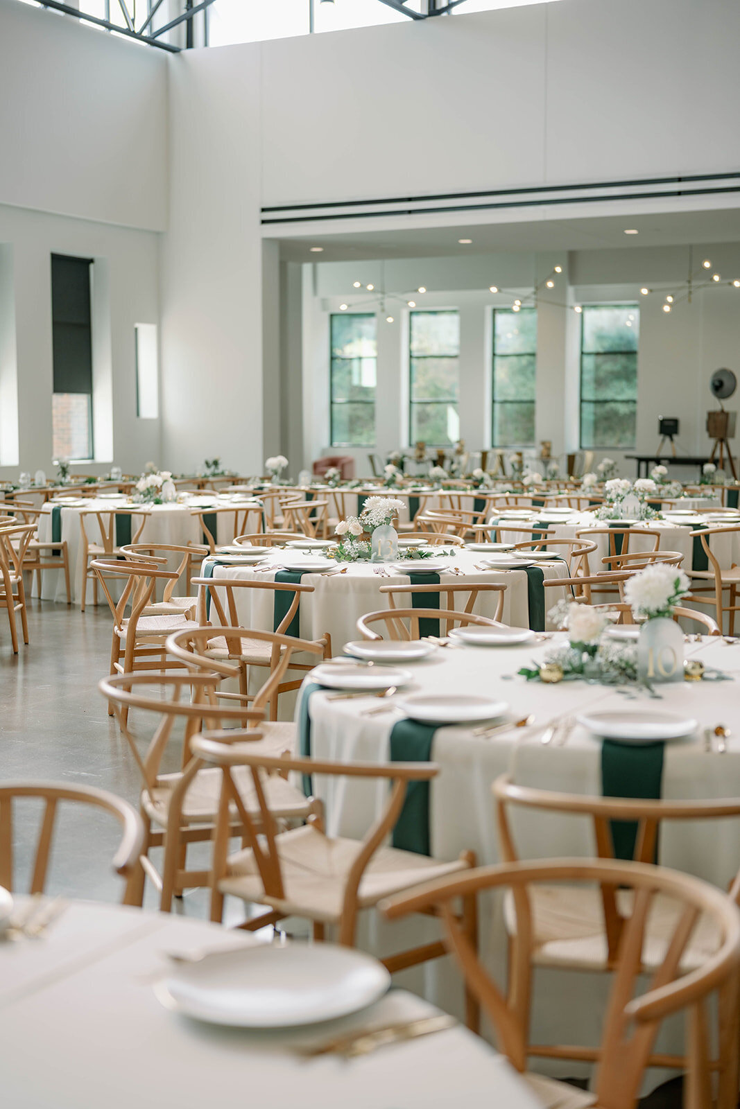 Wide view of the empty reception space at Leona Road showcasing elegant décor, wood tables, candles, and modern Grand Rapids wedding styling.