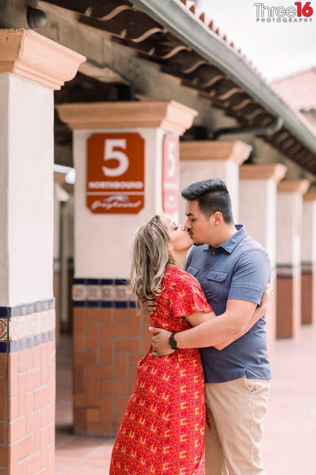 Engaged couple share a kiss on the dock at the Santa Ana Train Station