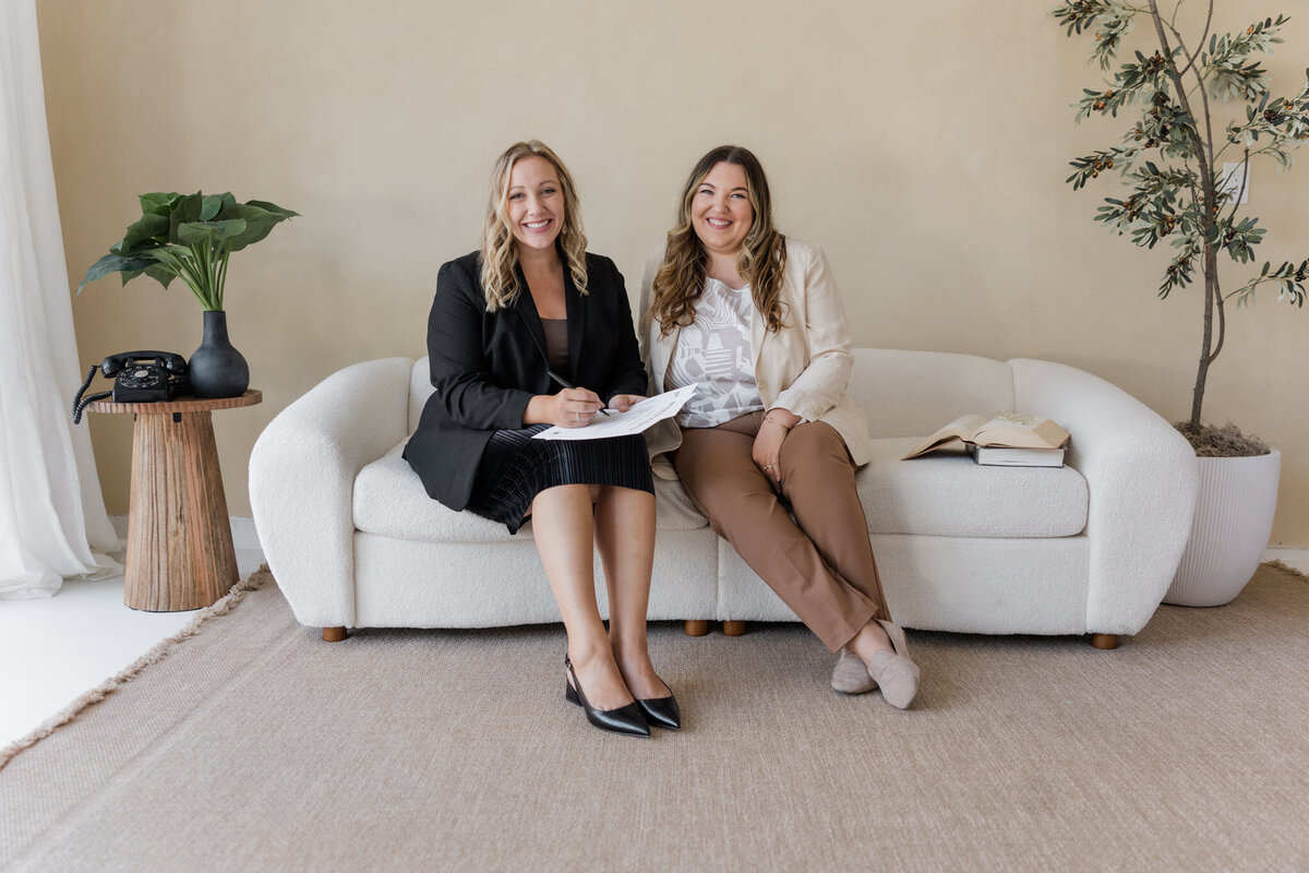 Small business lawyers, Paige Griffith & Alisha Suazo, pose for portrait on cream sofa