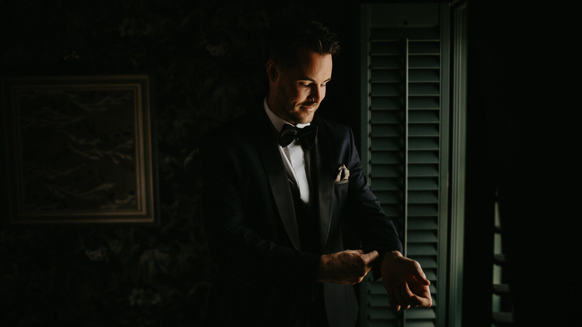Groom gets ready in the window or the Sun Street Hotel.