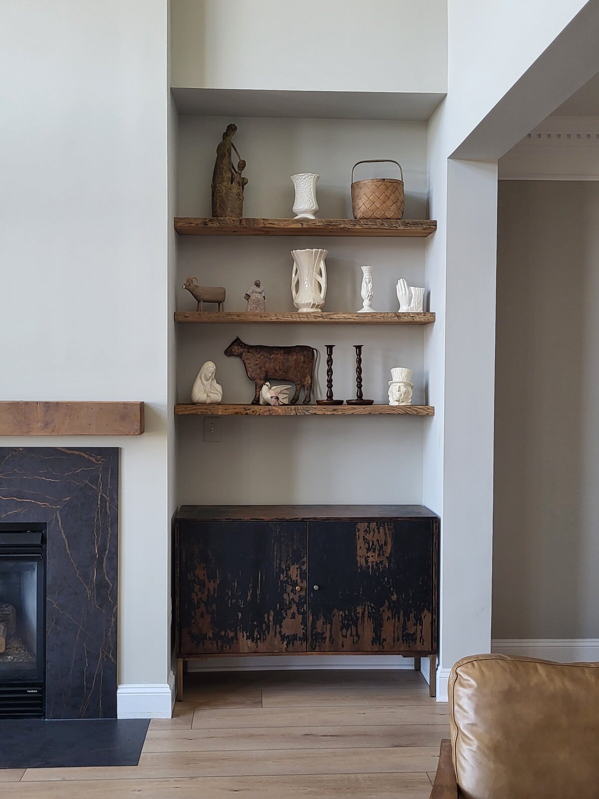 Fireplace sideview with antique wood mantle and antique wood bookshelves in the nooks beside the fireplace with artisticaly painted black and tan cabinets