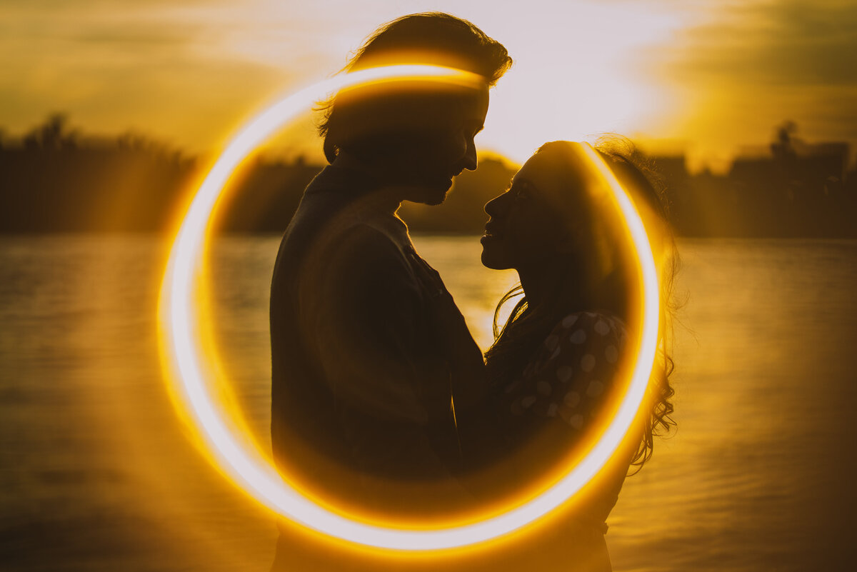 Engaged couple looking at each other at sunset using ring of fire technique with a copper pipe on lens