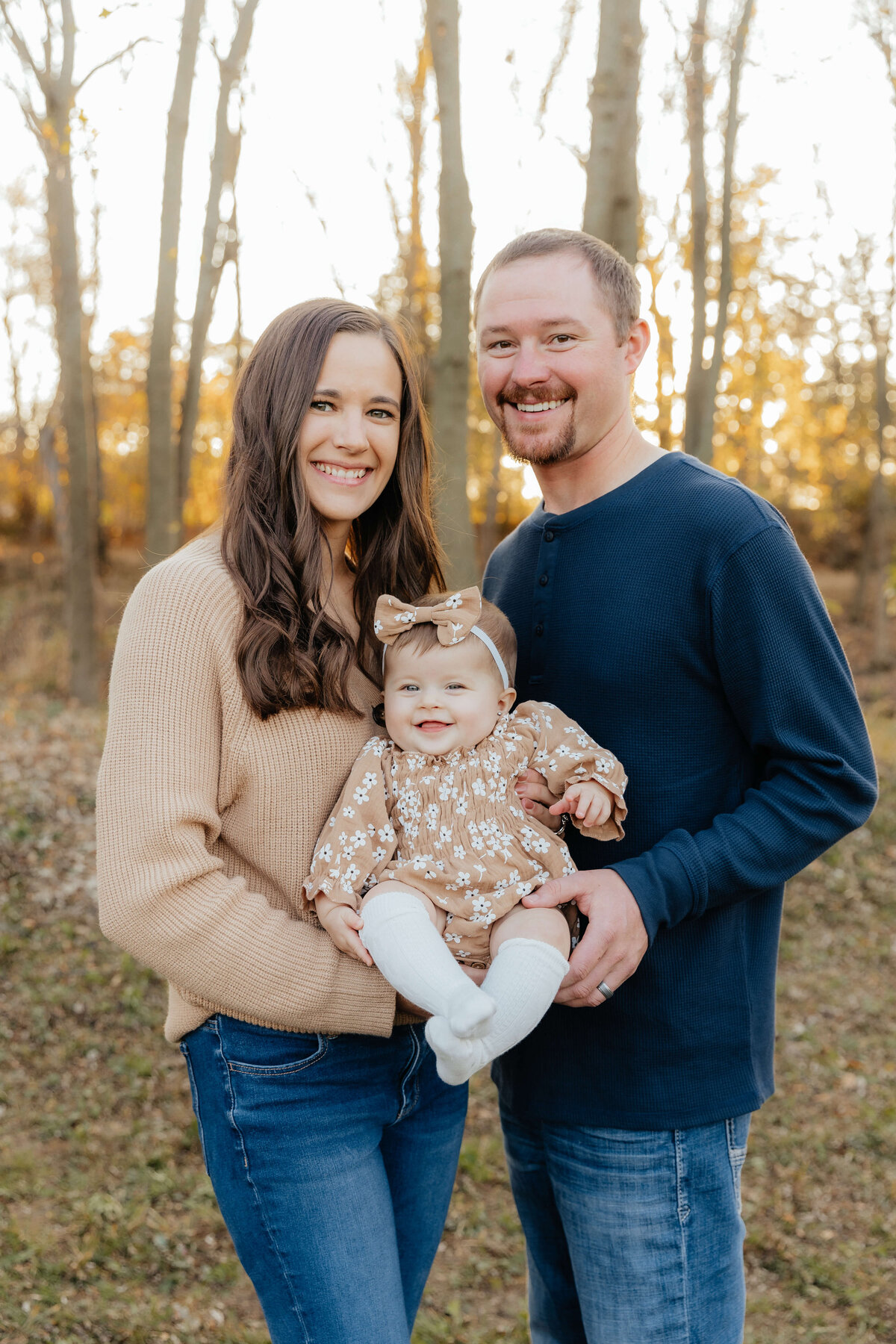 Smiling parents holding baby during autumn session, Ohio family photography for laid-back parents who love natural light and happy moments