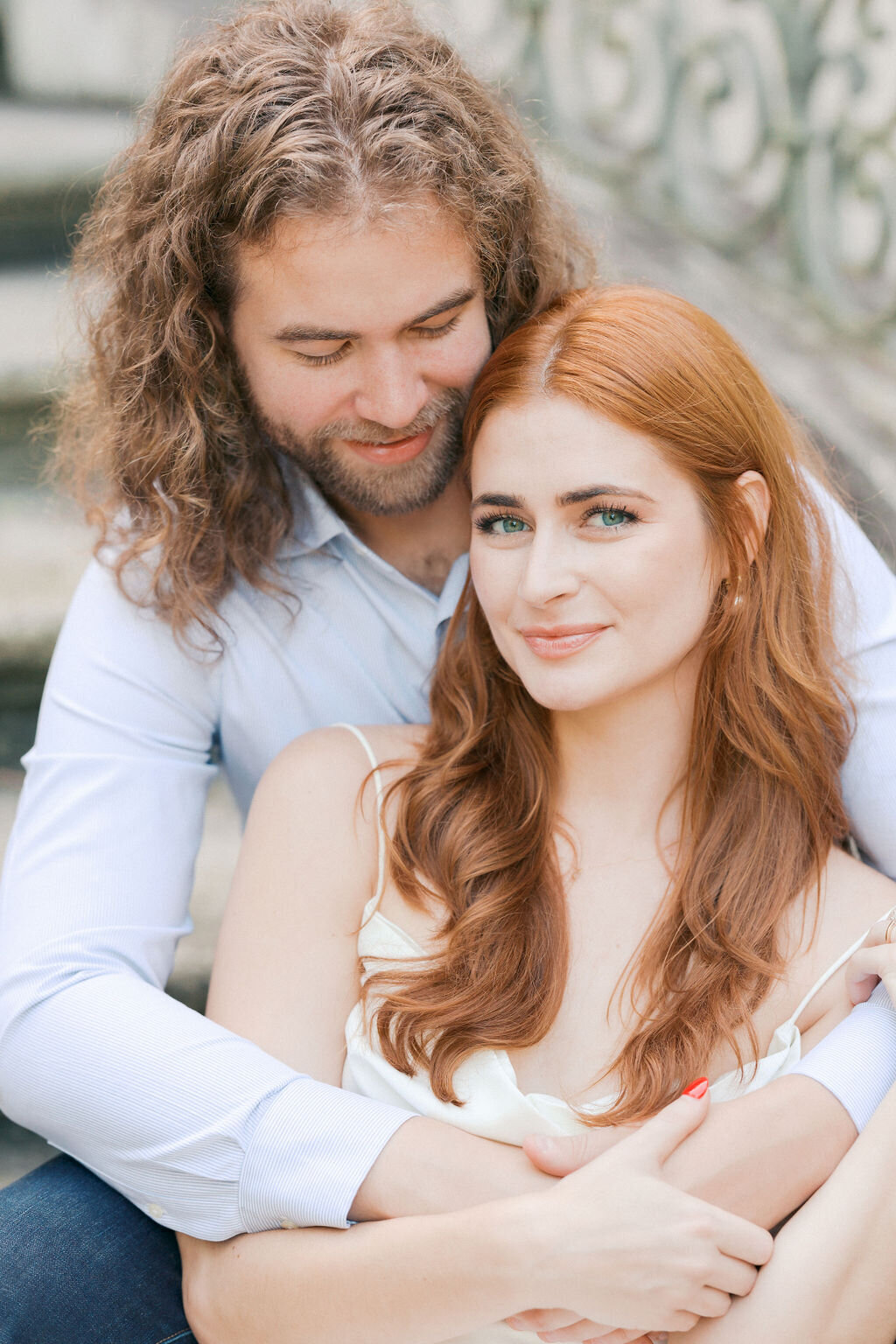 Guy laughs into temple of red head girl smiling at camera on the steps of the Atlanta History Center's Swan House