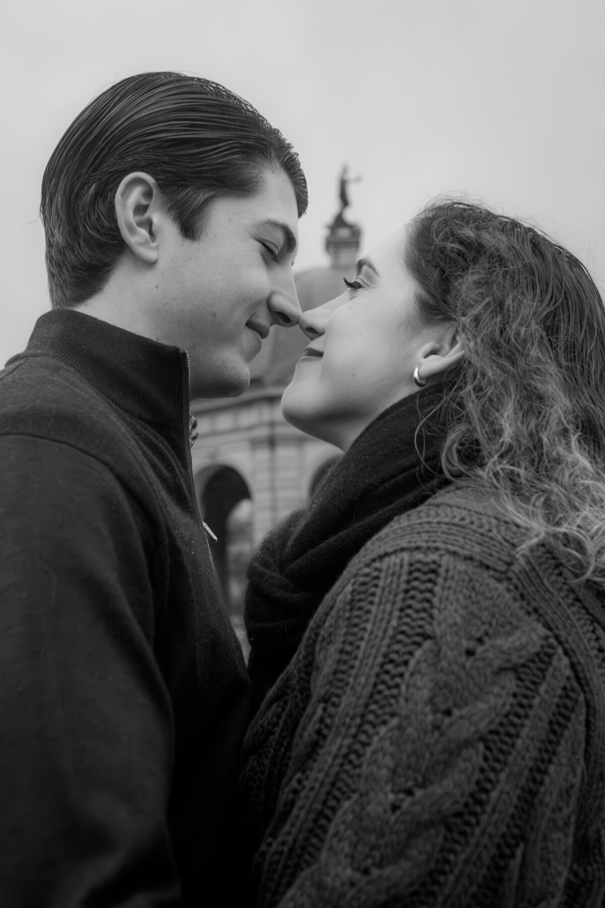 This couple holds their faces near to each other while standing in a close embrace.