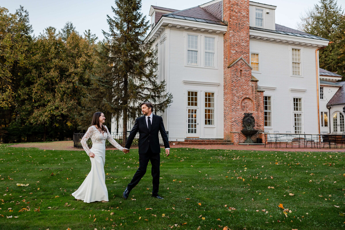 A couple celebrates their intimate fall wedding at a historic mansion in Stowe, Vermont, surrounded by vibrant autumn foliage and scenic mountain views

