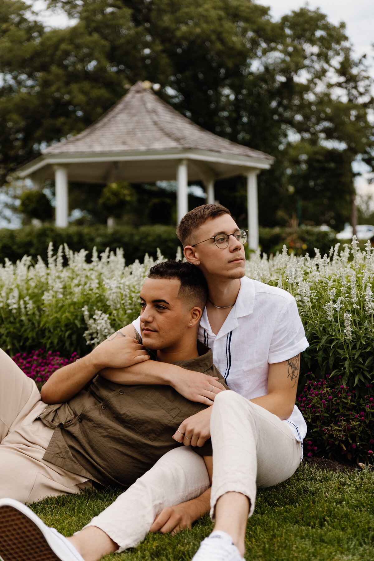 A couple sitting in a small garden area together while one leans back into the other