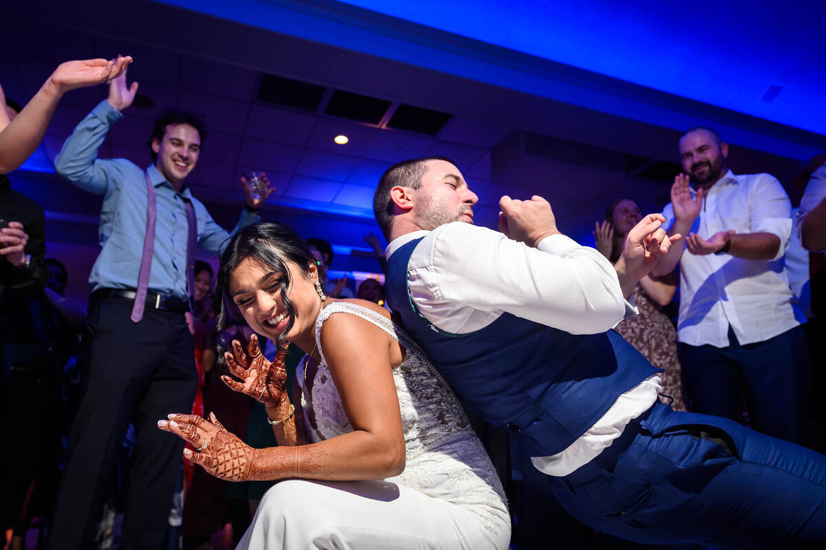 A bride and groom dance back to back on the dance floor