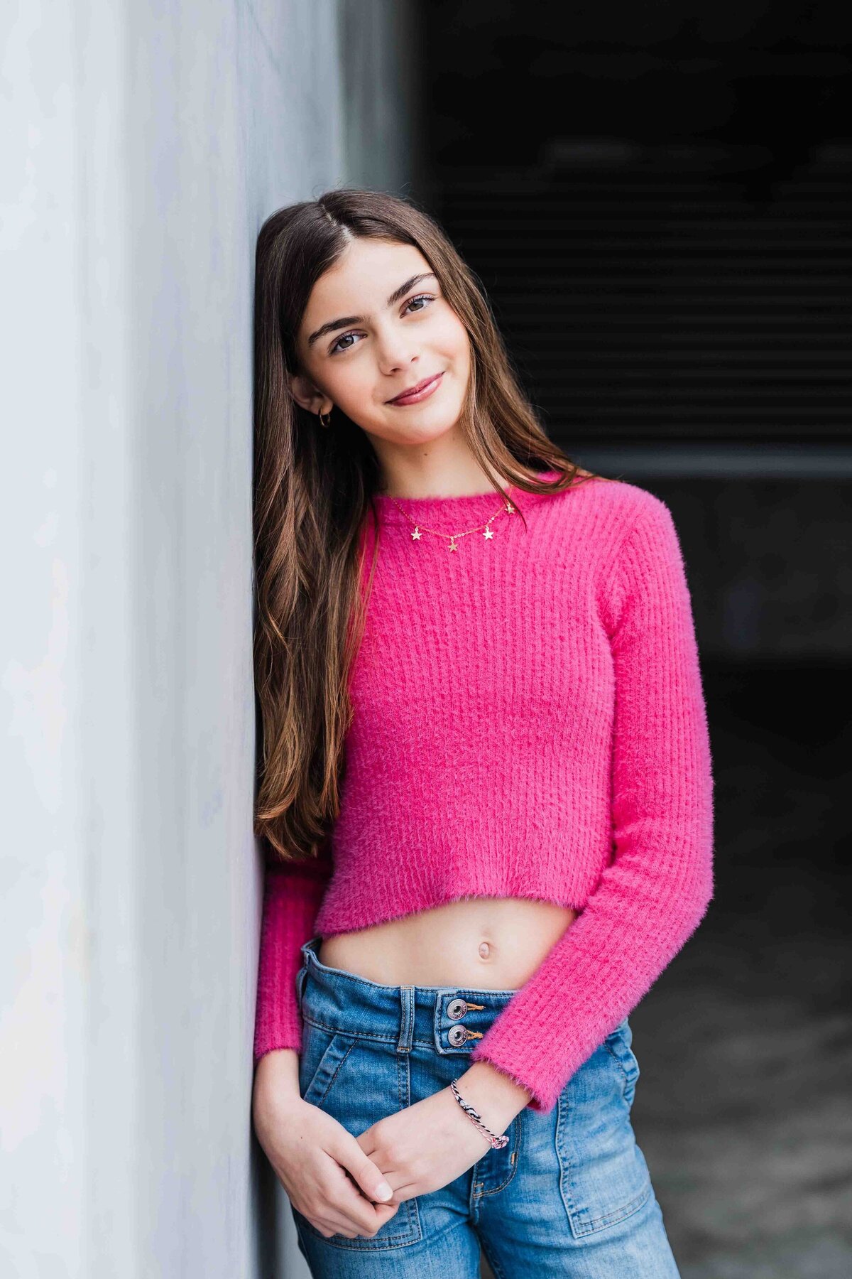 teenage-girl-pink-sweater-leaning-against-concrete-wall