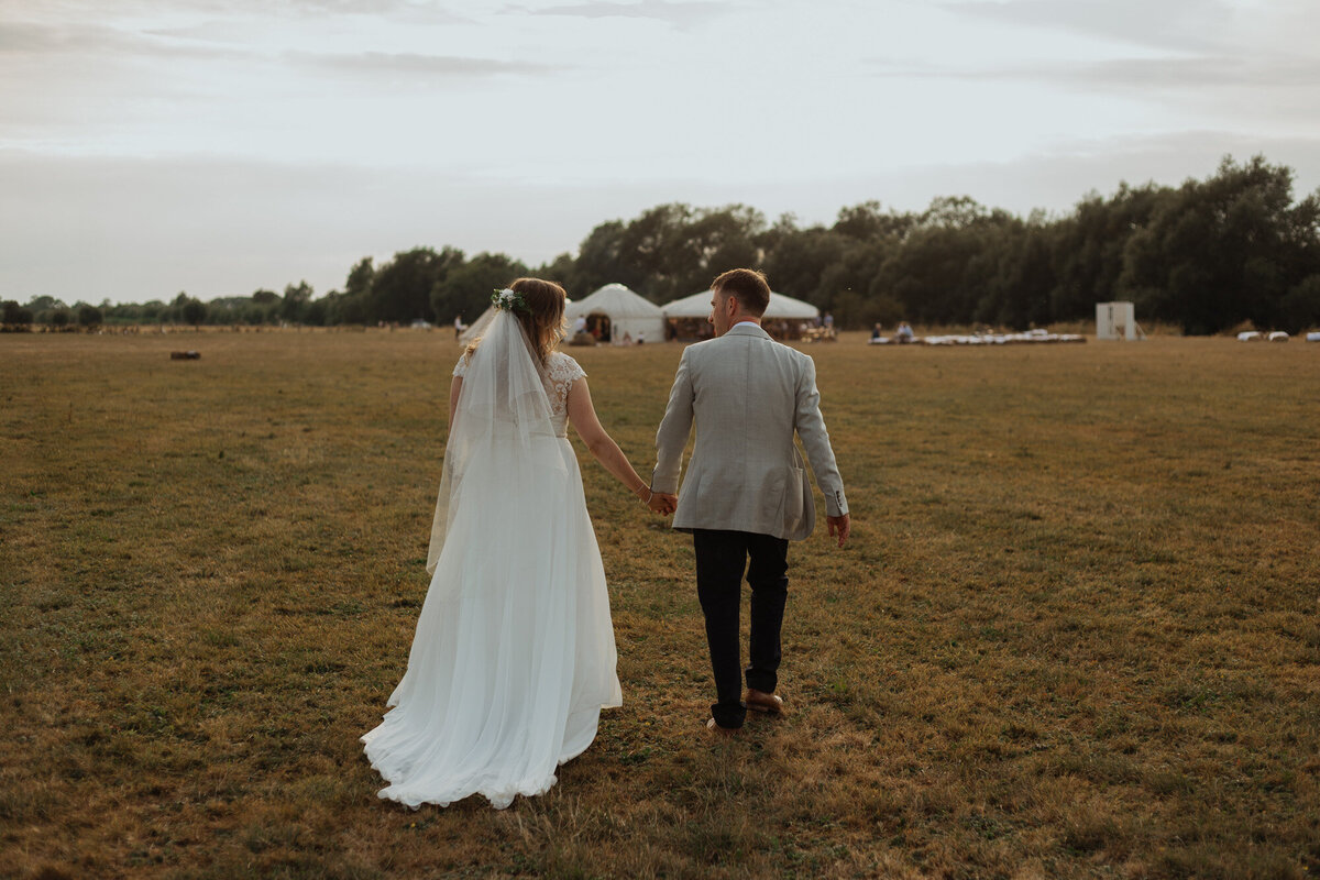 bride and groom walking in a field  together