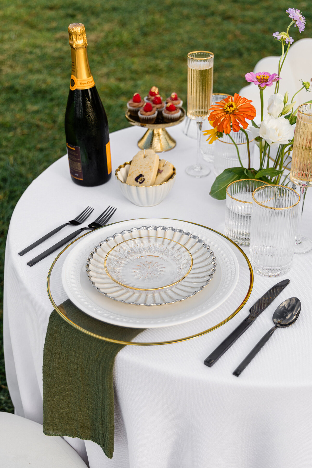 pink orange and white flowers on white table cloth with mixed metal place setting and tea cookies