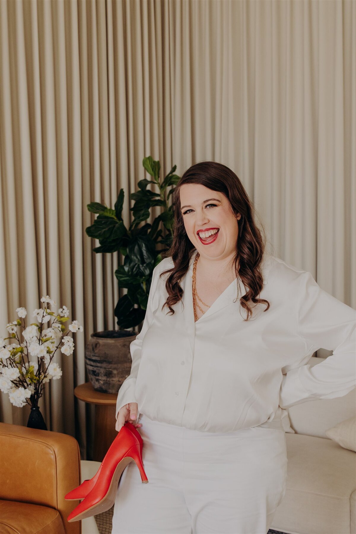 therapist in all white outfit smiling while holding a red shoe